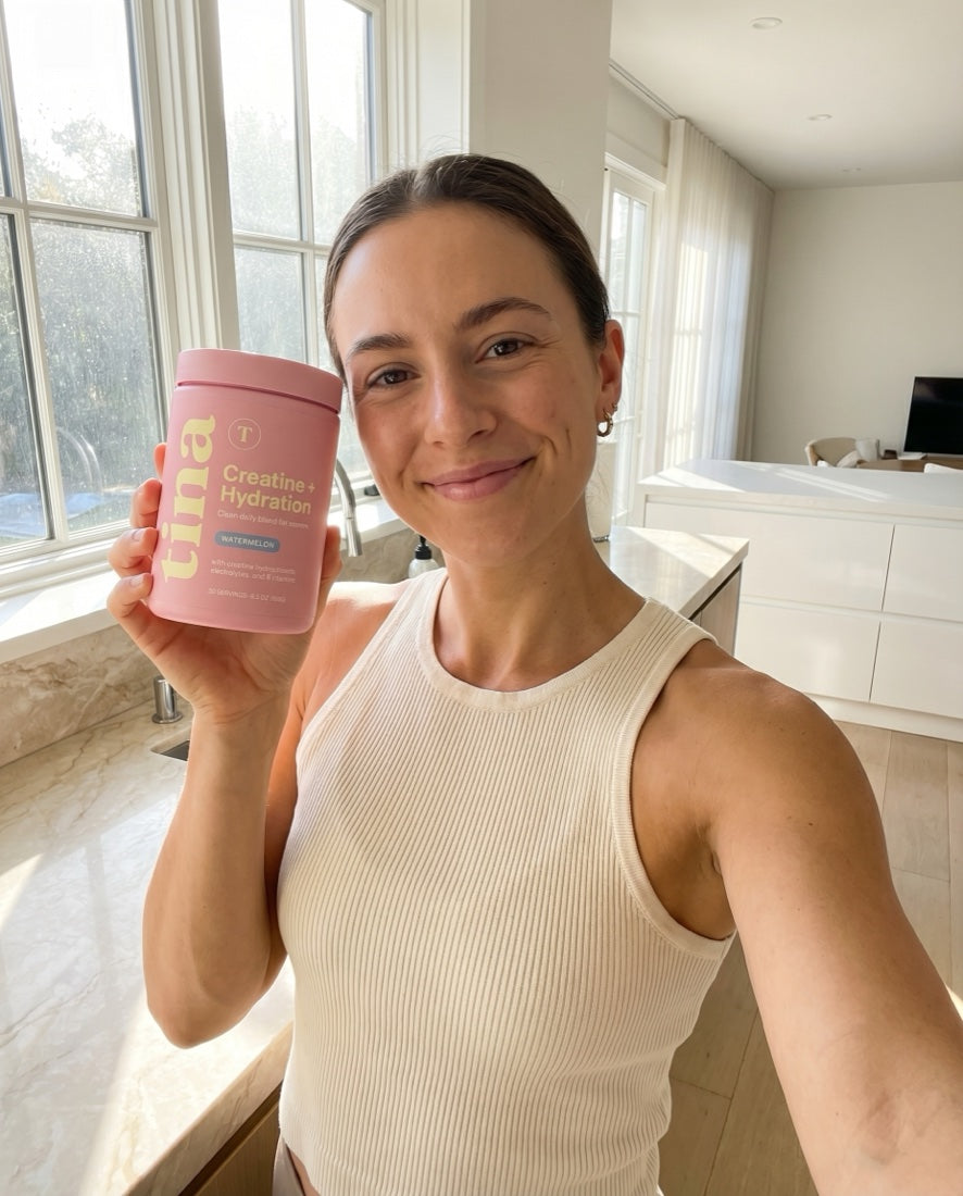 Woman holding the pastel pink TINA Creatine + Hydration jar in a bright kitchen